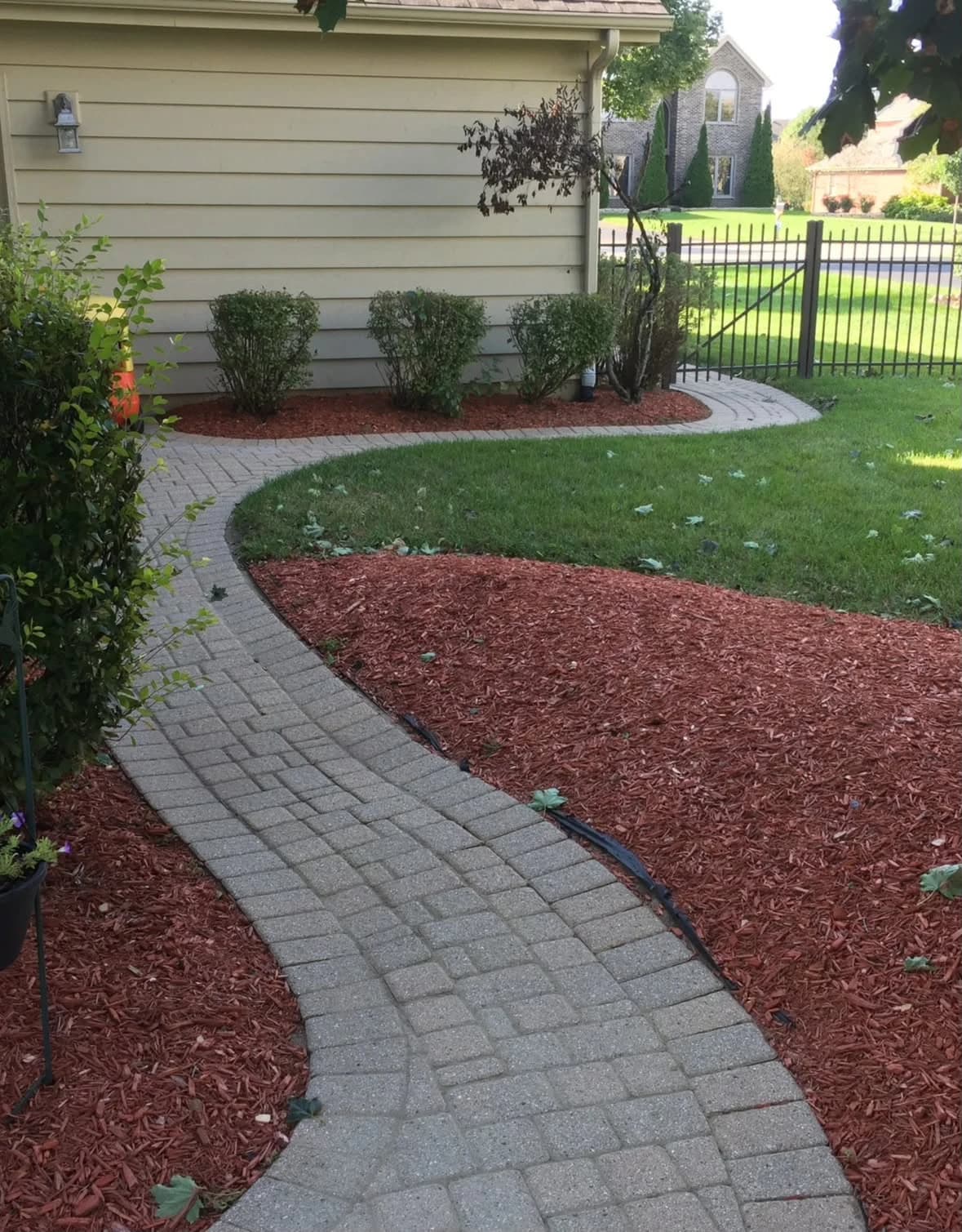 Red mulch beds beside a paver walkway